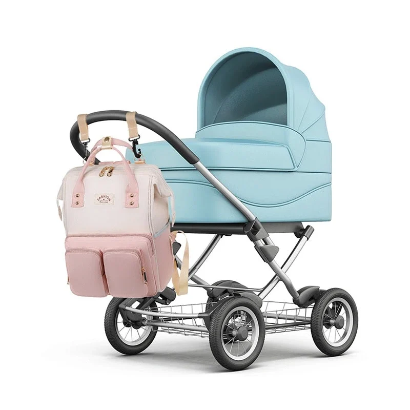 シルバーのフレームにライトブルーのバシネット・キャノピー、4つの大きな車輪、その下にワイヤー製の収納ラックを備えた、洗練されたデザインのモダンなベビーカー。ハンドルバーには、複数のポケットとベージュのストラップが付いたおむつバッグ用リュックサックが取り付けられています。