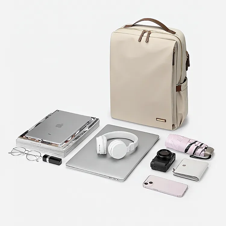 ベージュのビジネスリュックとパソコン、ヘッドホン、カメラ、折りたたみ傘、スマホなどの収納例を並べた女性用小さめリュック
