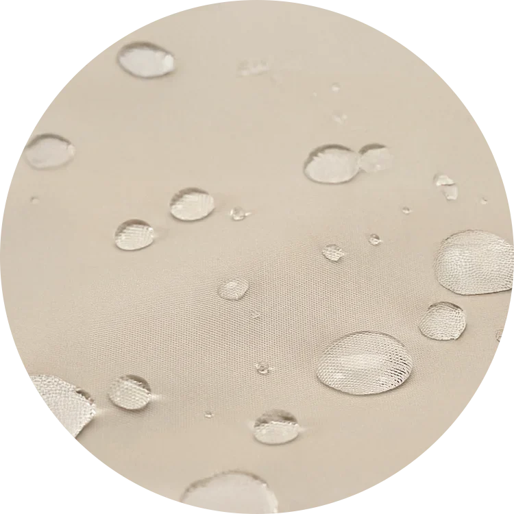 薄いベージュ色の生地に水滴がのり、水をはじく防水性を示している様子