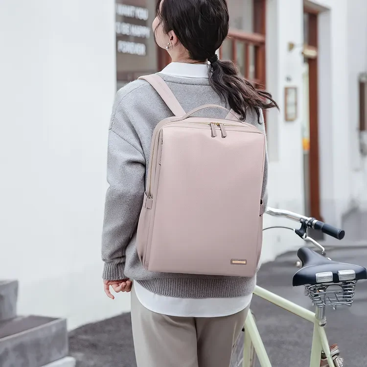 スモーキーピンクの軽量ビジネスリュックを背負い、自転車の横に立つ女性の後ろ姿