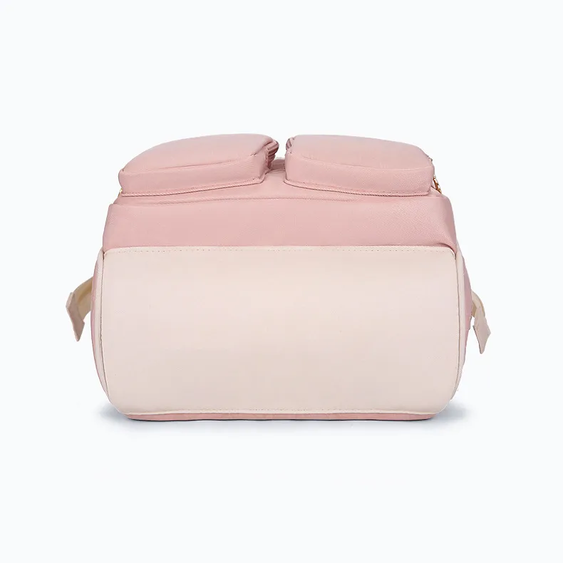 白い背景で撮影された、淡いピンクとクリーム色の育児用鞄。しっかりと自立するフラットな下側の構造とたっぷりとしたマチ幅が視覚的にわかります。