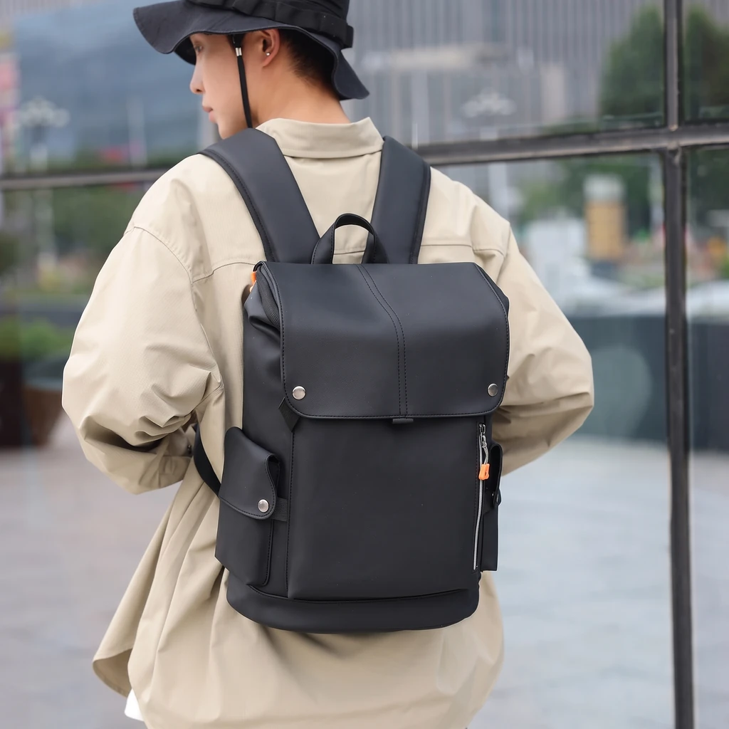 スタイリッシュなメンズ用20LのPUレザー製ビジネスリュック バケットハットとベージュジャケットを着た男性が、都会の街角でスタイリッシュな20LのPUレザー製ビジネスリュックを背負う姿。