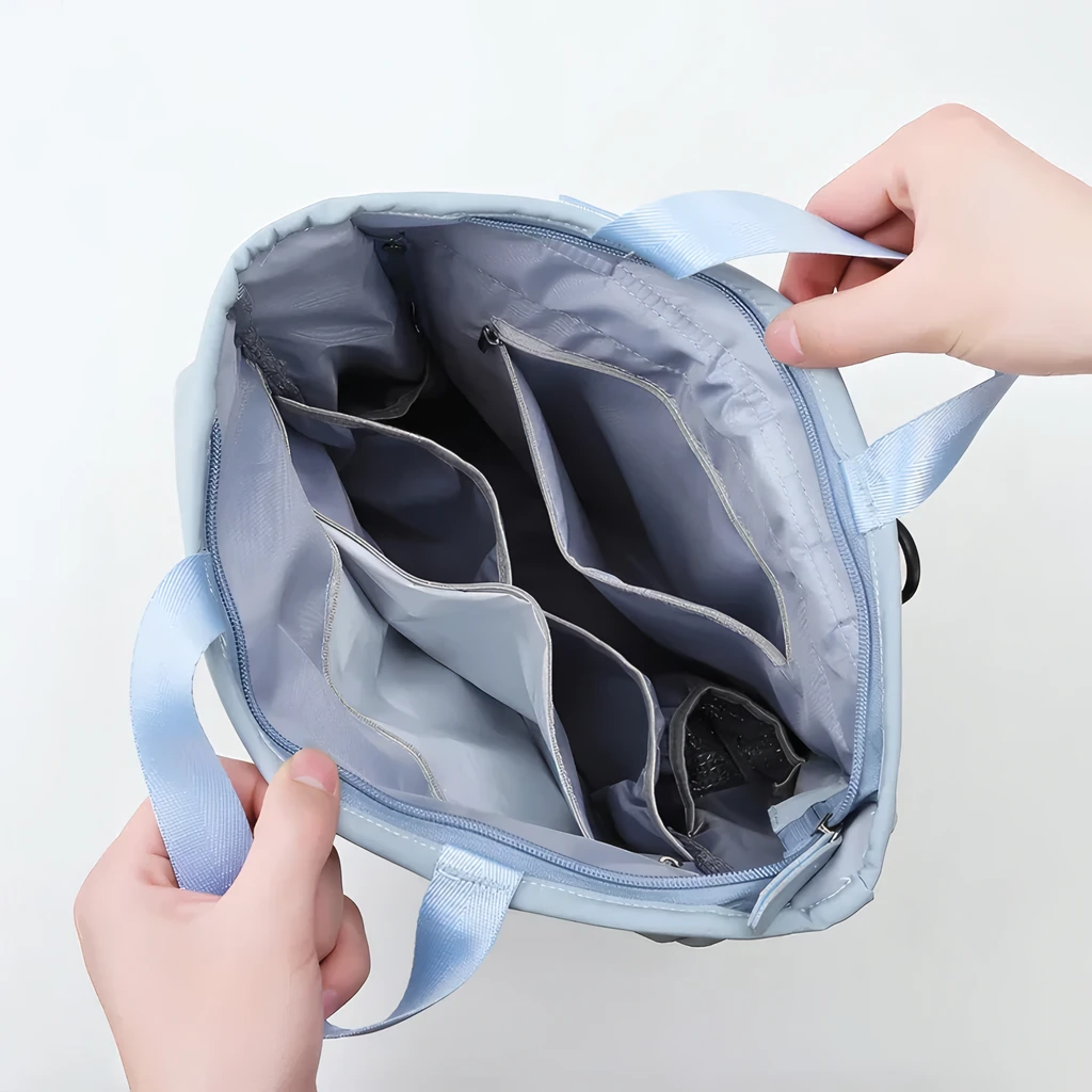 グレーの整理しやすい仕切り付きポケットが広々と開いて見える、軽量で防水仕様のおしゃれなマザーズリュックの俯瞰写真。