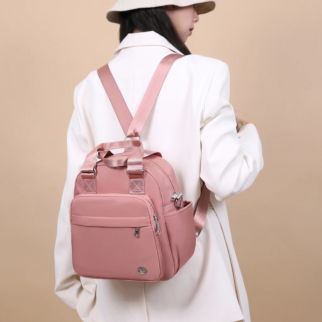 白ジャケットとベージュの帽子を合わせた女性が背負う、おしゃれで軽量なきれいめ防水リュック。日常の旅行に最適な後ろ姿。