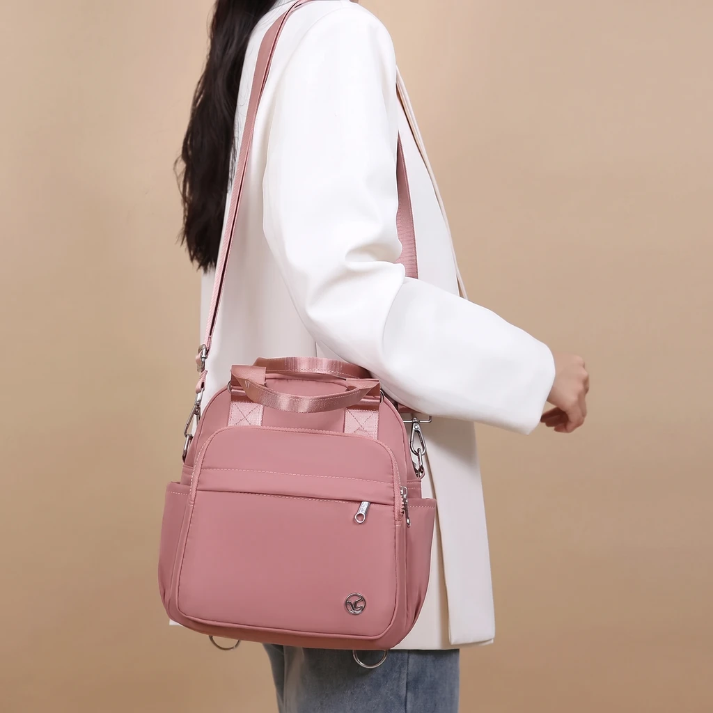 白いジャケット姿の女性が、ダスティローズのきれいめ防水バックパックを肩に掛けた、おしゃれでスタイリッシュなスタジオ撮影カット