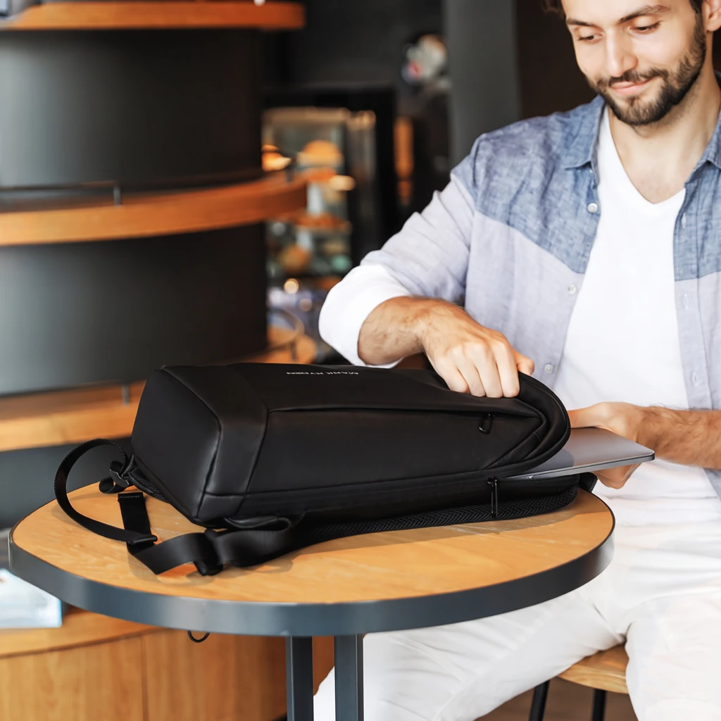 ノートPCの出し入れ カフェのテーブルでノートPCをリュックに入れる男性