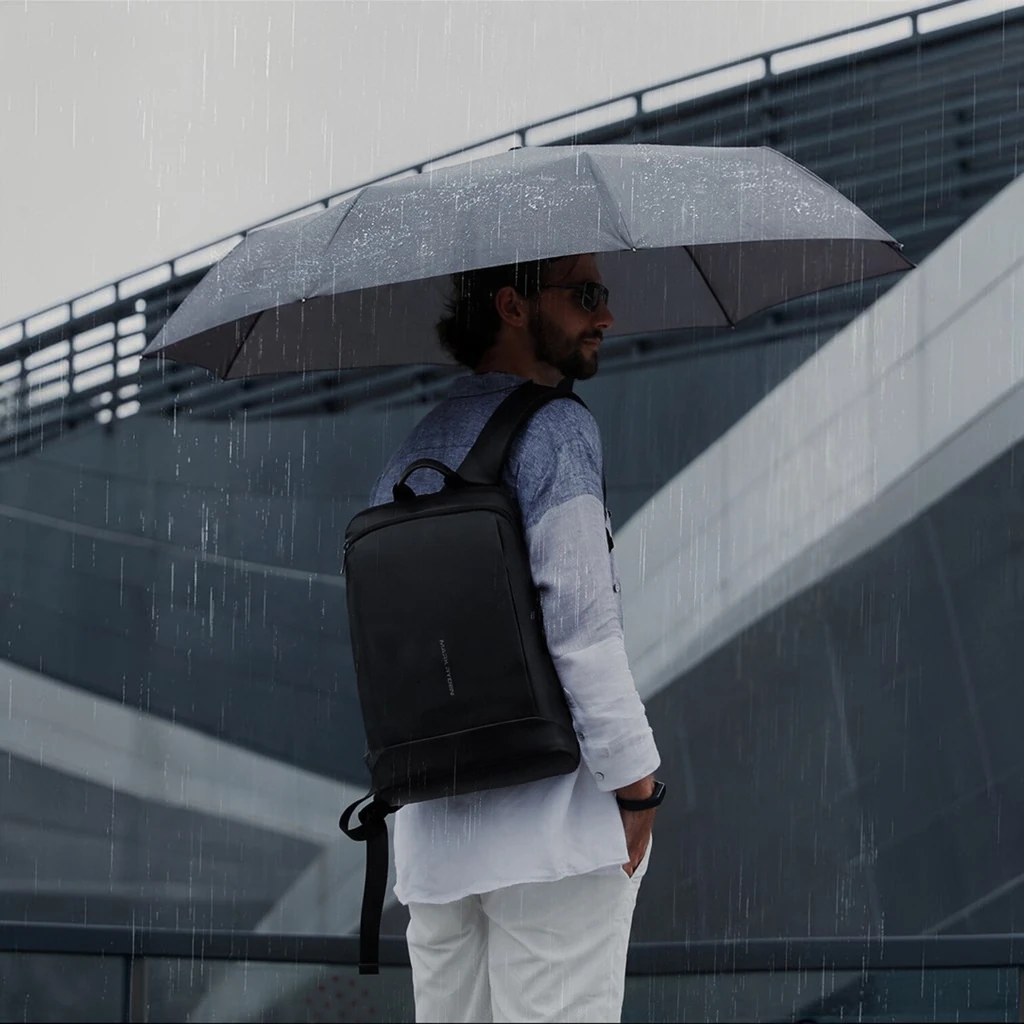 雨の日も使える生活防水 雨の日に傘をさして生活防水のリュックを背負う男性