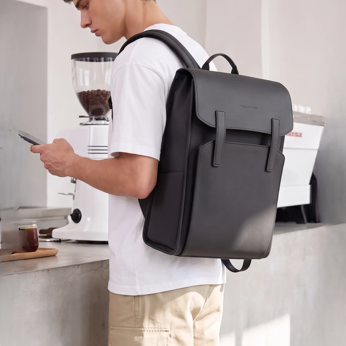 カフェのカウンターでスマホを見ながらリュックを背負う男性