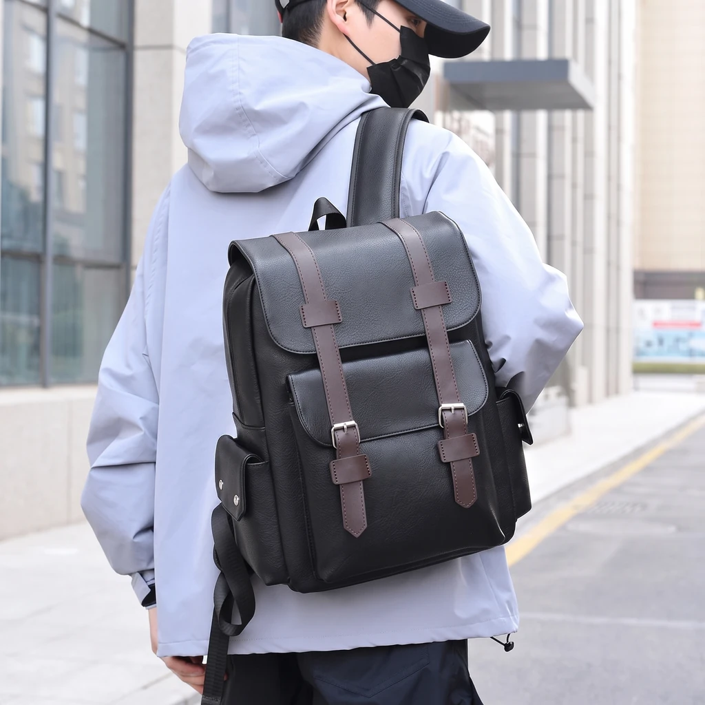 グレーのフード付きジャケットを着た男性が、スタイリッシュな20L防水レトロレザーバックパックを背負って、モダンな都市の街路を歩く様子。