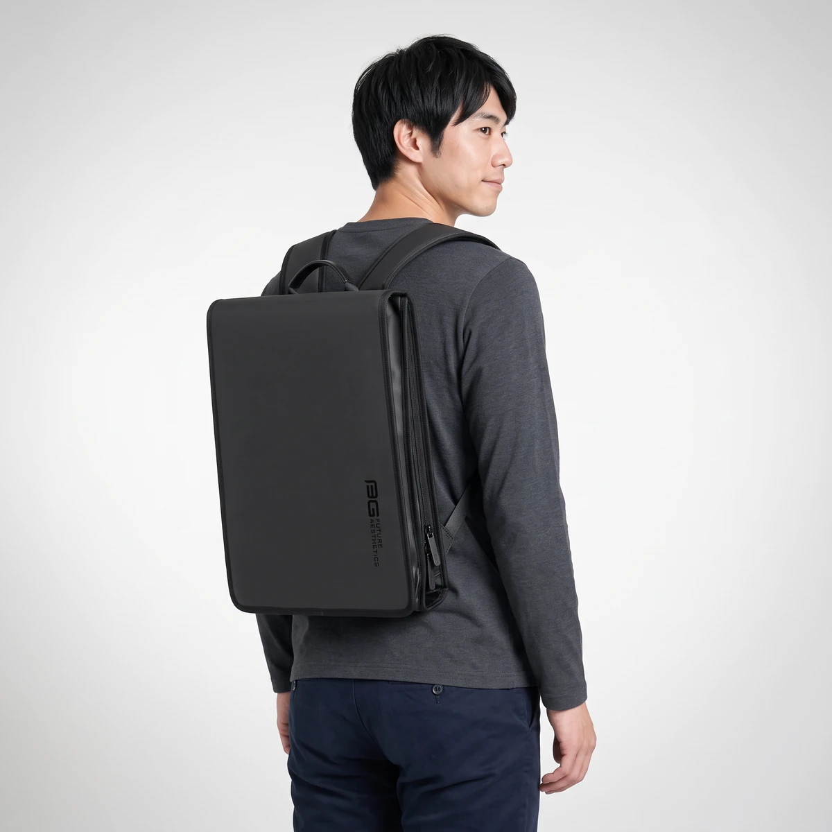 ブラックの薄型ビジネスリュックを背負った斜め後ろ姿。マチ8cmのスリムなシルエット