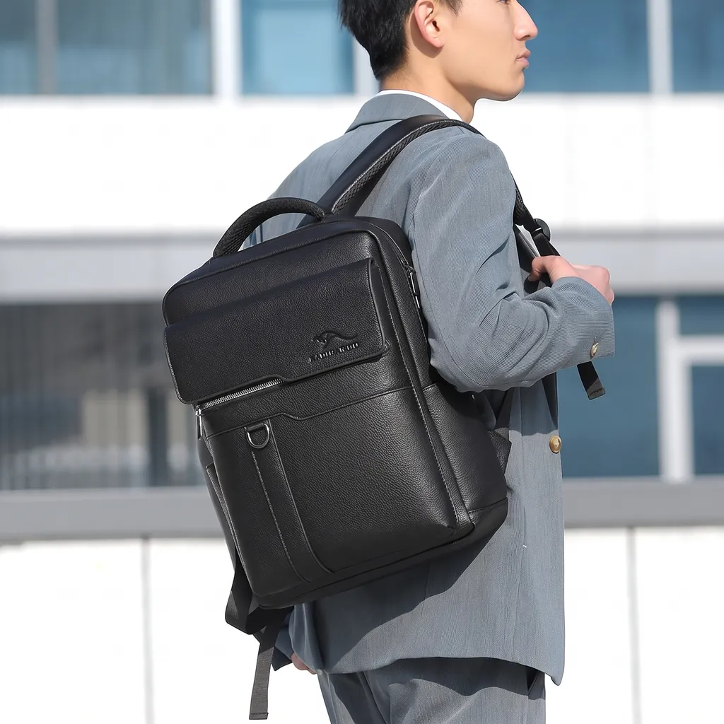 グレーのスーツを着た男性ビジネスマンが背負う、おしゃれで機能的なメンズ向け本革ビジネスリュックサック。背景には近代的なオフィスビル。
