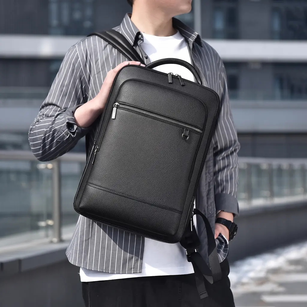 洗練された都会のビル群を背に、グレーのストライプシャツを着た男性が背負う16インチPC対応の20L多機能ビジネスリュック。
