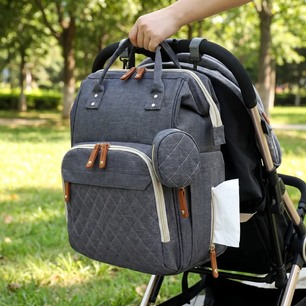A quilted mother's backpack with cooler hanging on a stroller in a park