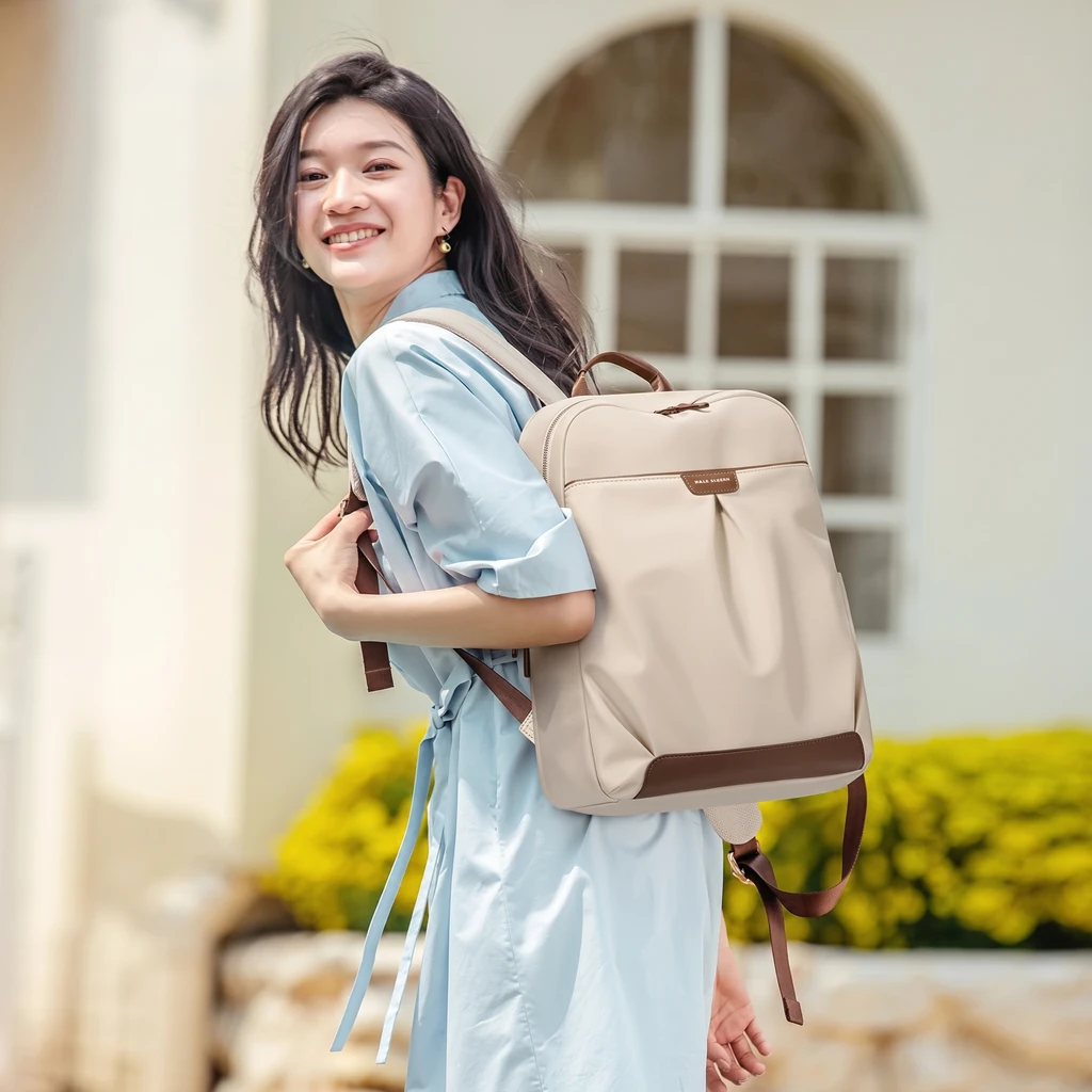 15インチPC対応 おしゃれなレディース 20L リュック 明るい日差しの下、水色のドレスを着て笑顔で振り返る女性が背負う、15インチPC対応のスタイリッシュな20Lレディースリュック。