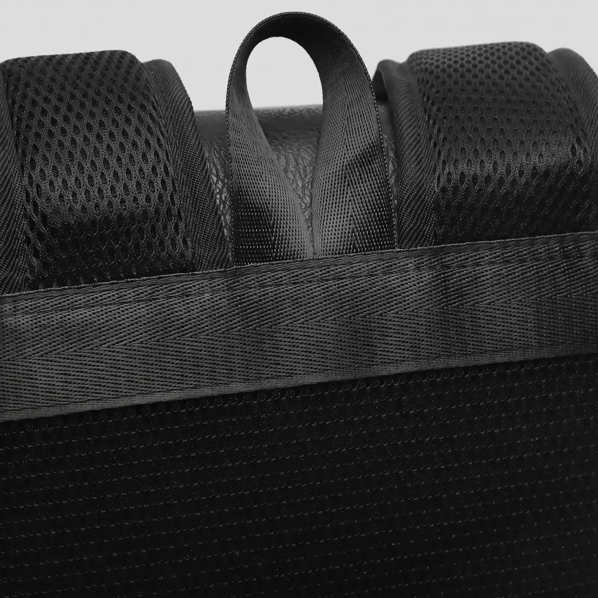 黒いレザーリュックの背面、通気性に優れたメッシュ素材のショルダーストラップと持ち手のアップ。