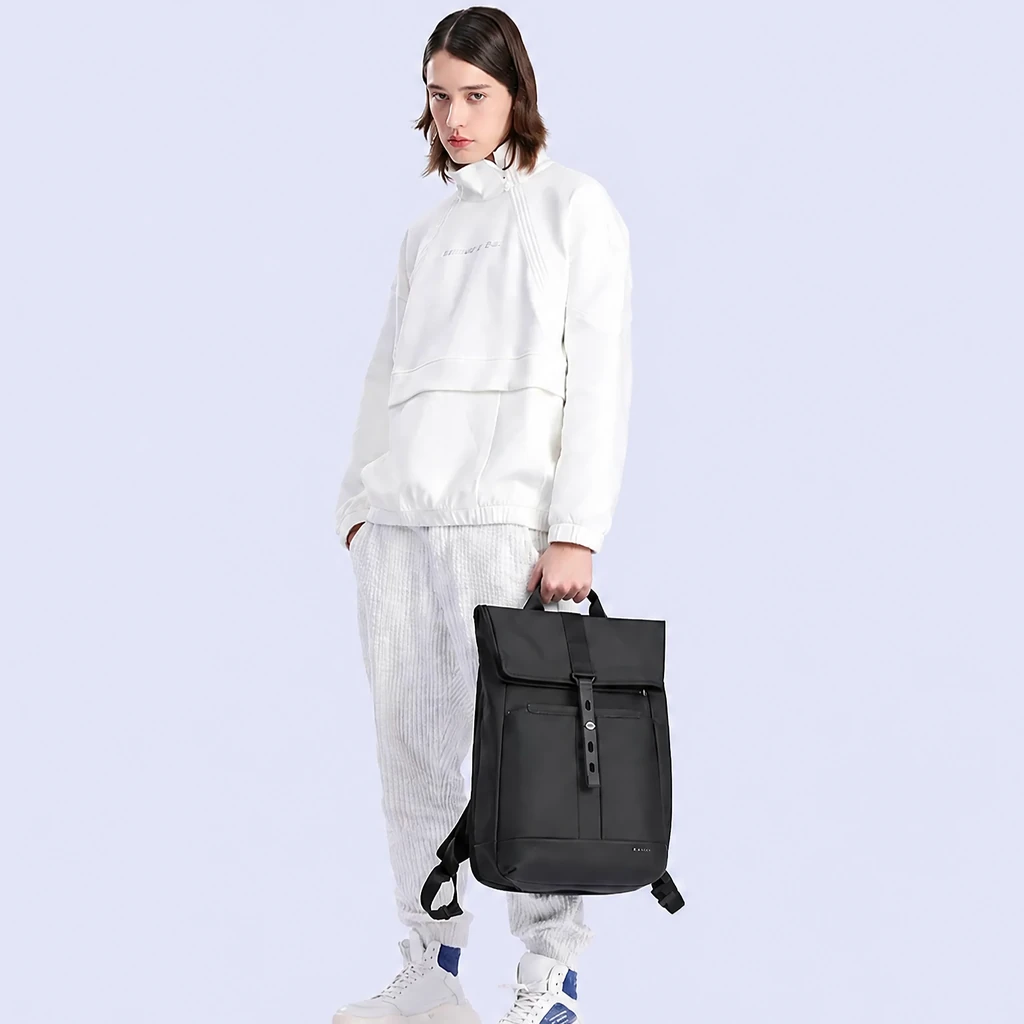 洗練されたスタジオで、白い服を着たモデルが手にする20L防水仕様のスタイリッシュなメンズビジネスバックパック。