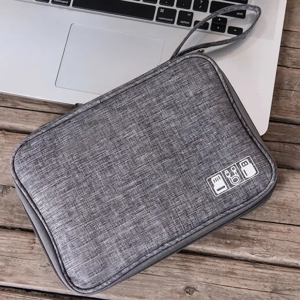 温かみのある木製テーブルの上にノートPCと並べて置かれた、生活防水仕様のスリムなガジェットポーチ