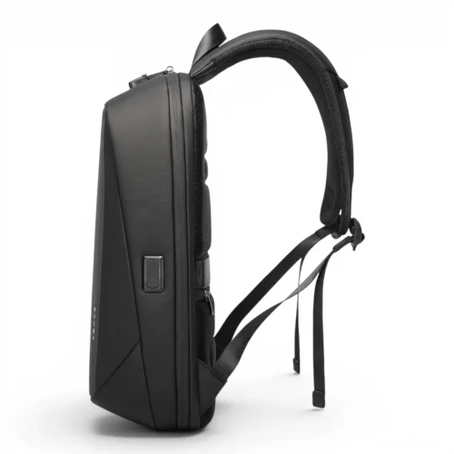 防水仕様のメンズスマートPCバックパック 20L 白い背景に立つ、USB充電ポートとクッション性の高いショルダーストラップを備えた黒いハードシェルバッグの側面図。