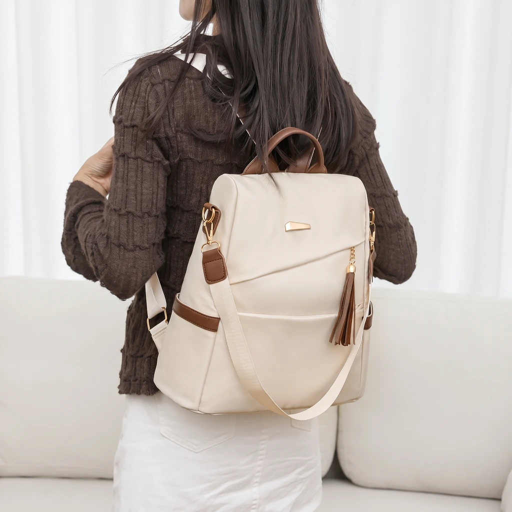 おしゃれな20L超軽量レディースリュック 温かい自然光が差し込む明るいリビングで、おしゃれな超軽量20Lレディースリュックを背負った、ブラウンセーターを着た女性。