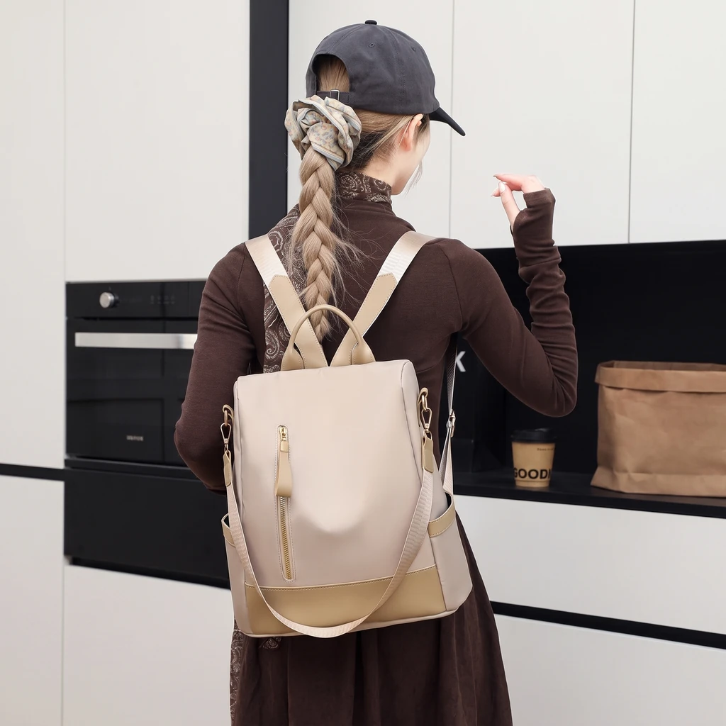 モダンなキッチンで大人可愛い防水20Lレディースリュックを背負うおしゃれな女性の姿。カフェ風のカジュアルな雰囲気が漂う日常の一コマ。