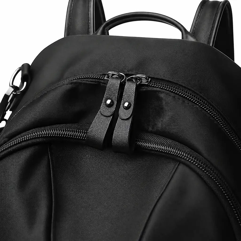 撥水ナイロン素材を使用した女性用15Lミニバックパックの、ダブル黒ジッパーと特徴的なテクスチャ加工引き手部分のマクロズームアップ
