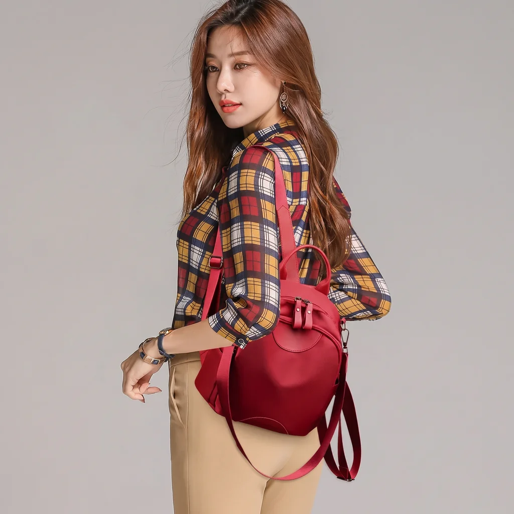 チェック柄シャツとベージュのパンツを着た女性が背負う、撥水性に優れたおしゃれな15L軽量レディースナイロンミニリュック。
