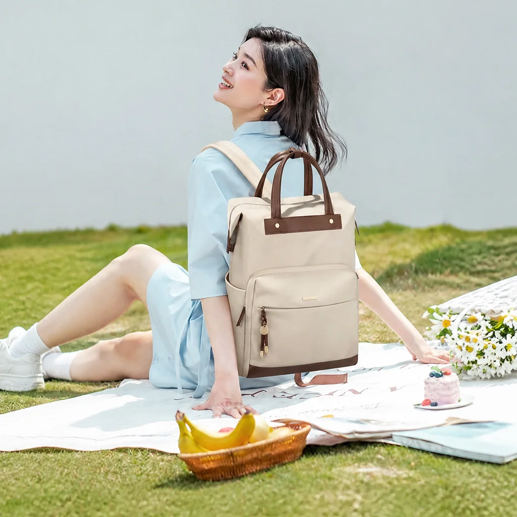 芝生の上でピクニックを楽しみながら、撥水加工が施されたおしゃれな15.6インチレディース通勤リュックを背負って笑顔で座る女性